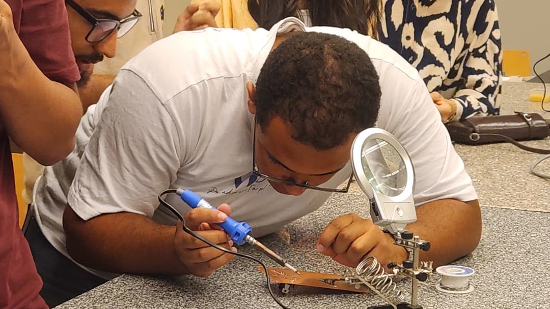 AUC Robotics member soldering on a solderable breadboard.